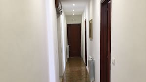 A hallway with white walls, a tiled floor, and wooden doors. - Al Chiaro di Luna (Taormina)