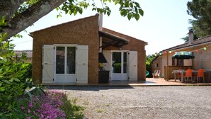 A small, single-story building with a gravel driveway and a patio area. - Gîte with barbecue and enclosed terrace close to shops and rivers (Lagorce)