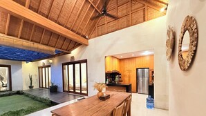 A spacious kitchen with wooden cabinets, a stainless steel refrigerator, and a dining area with a wooden table and chairs.