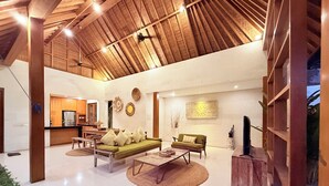 A spacious living area with a high ceiling, a sofa, a coffee table, and a television.