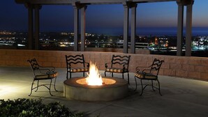 A fire pit with three chairs and a pergola overlooking a cityscape at dusk. - Grand Pacific Palisades Resort - 2 Bedroom/2 Bath - LAST MINUTE SPECIAL!!! (Carlsbad)