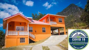 Una casa naranja de dos pisos con techo rojo, un balcón y una escalera que lleva al piso superior.