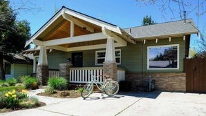 Ein eingeschossiges Haus mit Veranda, einem Stein-Schornstein und einem Fahrrad davor.