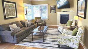 Ein Wohnzimmer mit zwei Sofas, einem Couchtisch, einem Fernseher und einem Kamin.