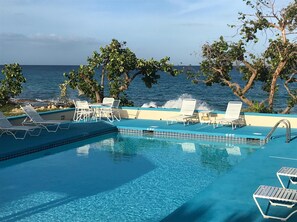 Relax by the serene pool, surrounded by lounge chairs and offering ocean views.