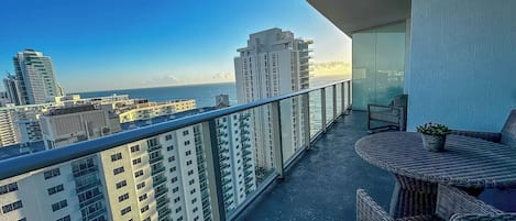 A balcony with a view of the ocean and high-rise buildings.