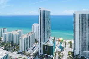 A high-rise hotel with multiple floors, a swimming pool, and a view of the ocean.