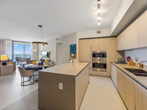 Una cocina moderna con una isla central, electrodomésticos de acero inoxidable y armarios de madera.