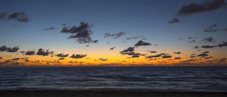 A beach with a sunset and clouds.