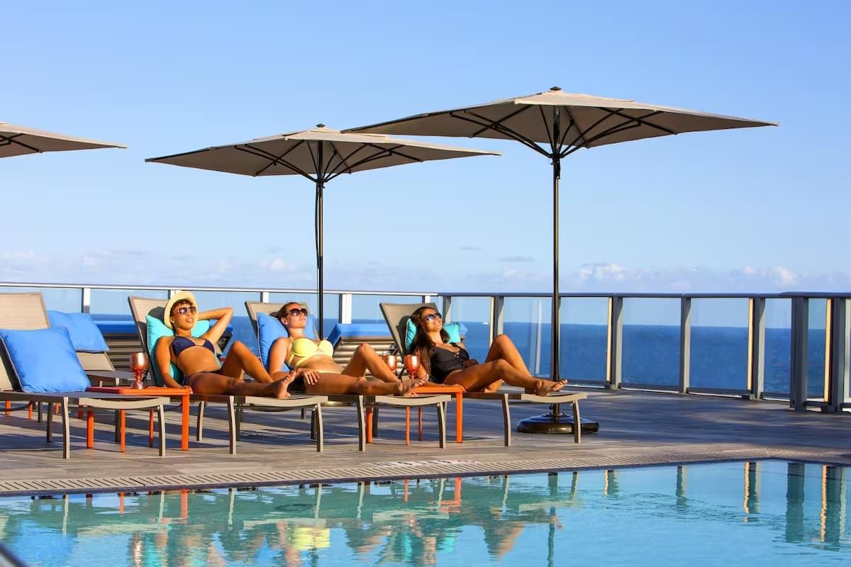 Un espace aménagé au bord de la piscine, avec des chaises longues et des parasols, donnant sur une étendue d’eau.
