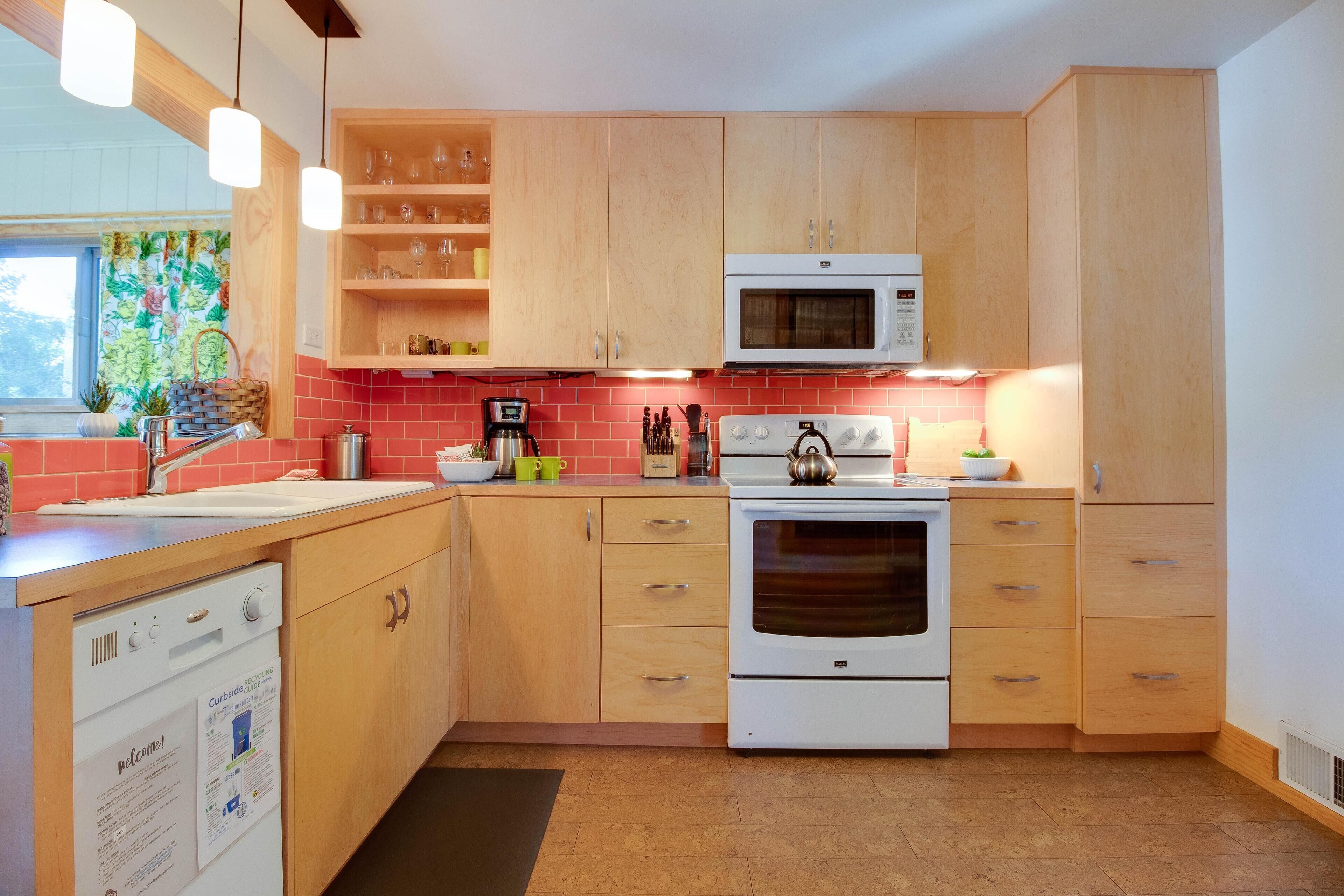 A modern kitchen with wooden cabinets, a white microwave, a stove, and a dishwasher.