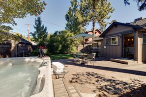 A backyard with a hot tub, patio furniture, and a barbecue area.