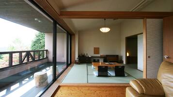 Un interno moderno con pavimento in legno, sedute in tatami, un divano in pelle e un'area pranzo con tavolo e sedie.