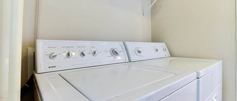 A front-loading white washer and dryer unit with control knobs and a water level indicator.