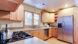 Une cuisine moderne avec des meubles en bois, des appareils électroménagers en acier inoxydable et une grande fenêtre qui laisse entrer la lumière naturelle.