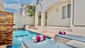 A pool area with a stone wall, lounge chairs, and a towel. - Experience Luxury on the Island of Isla Mujeres  (ISLA MUJERES)