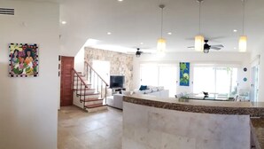 A spacious living area with a kitchen island, a staircase, and a dining area. - Experience Luxury on the Island of Isla Mujeres  (ISLA MUJERES)