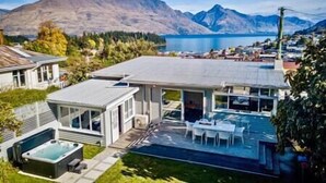 Una casa moderna con un amplio patio trasero, un jacuzzi y vistas a montañas y un lago.