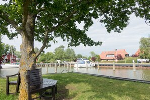 A lakeside park with a bench, a tree, and a dock with boats.