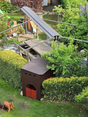Ein Spielplatz mit Rutsche, Klettergerüsten und einem kleinen Holzhaus.