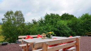 Ein Holztisch mit Bänken, einer Laterne und einem Blumentopf.