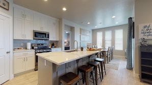 A spacious kitchen with white cabinets, a central island with stools, a microwave, and a stove. - Endless Adventures-Pool is Open! (Washington)