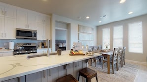 A modern kitchen with white cabinetry, a stainless steel stove, and a large island with bar stools. - Endless Adventures-Pool is Open! (Washington)