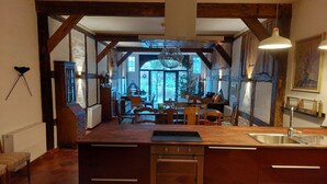 Cucina con isola centrale, travi in legno e vista su zona pranzo.