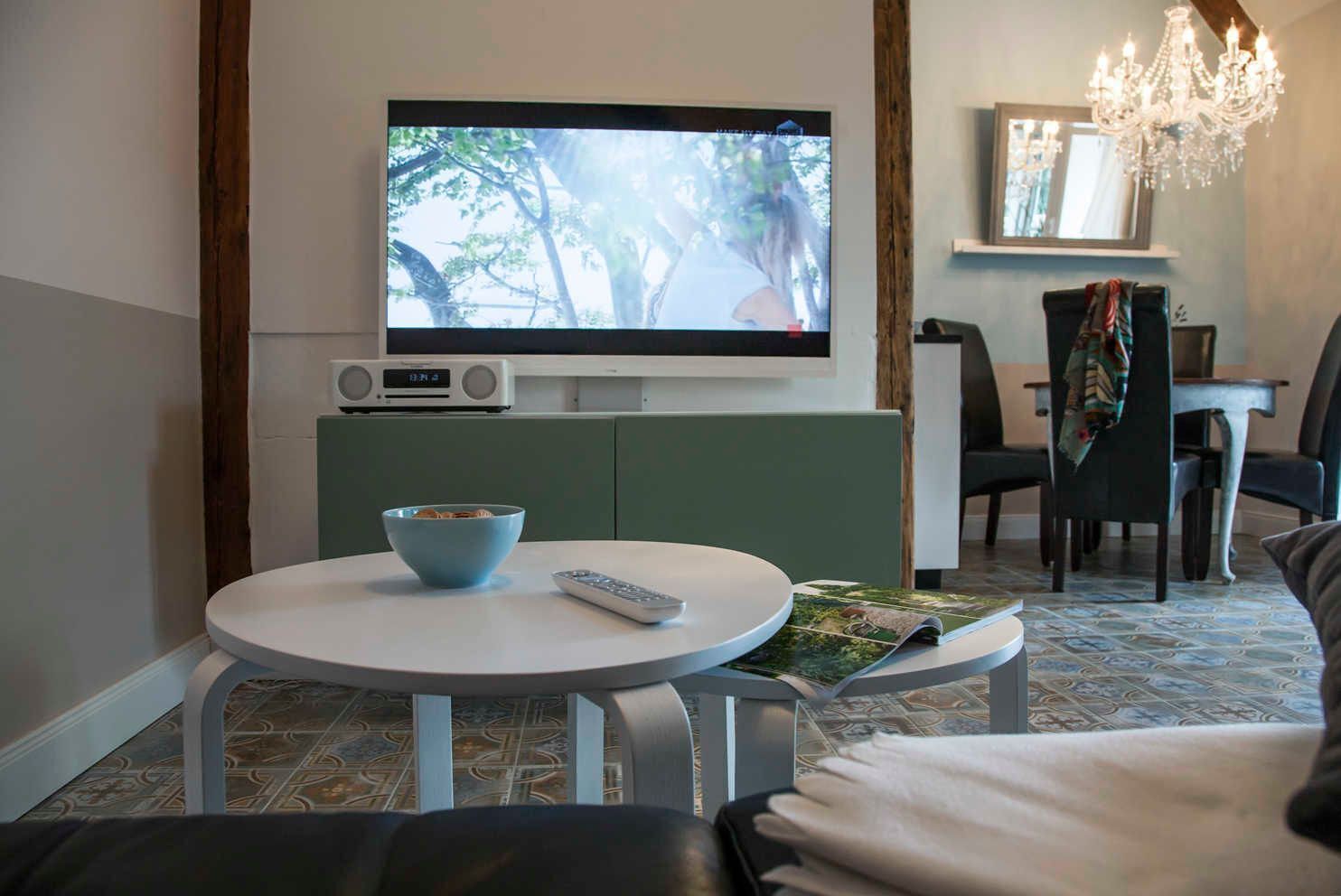 Un salon avec un téléviseur fixé au mur, un bol de céréales sur une table et un magazine.