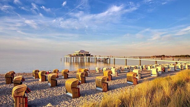 Una spiaggia con cabine e un molo che si protende nell'acqua.