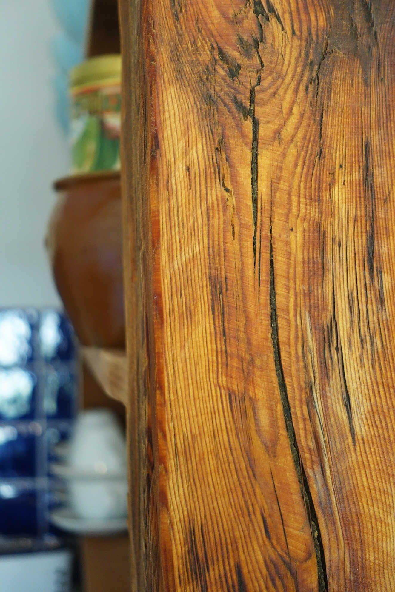 Un gros plan d’une surface en bois, où l’on peut distinguer les motifs du grain et les fissures.