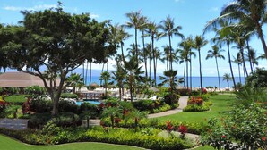 A resort with a pool, palm trees, and a view of the ocean.