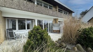 A modern house with a patio, a dining table with chairs, and a chimney. - Luna22 (room category) - Luna III (Sankt Peter-Ording)