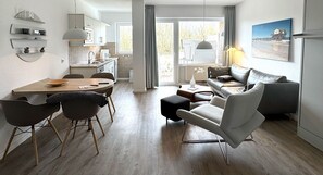 Eine moderne Küche mit Essbereich, einer Couch und Blick ins Freie.