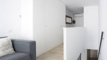 Una sala moderna con un sofá gris, una mesita redonda y un armario blanco.