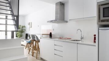 A modern kitchen with white cabinetry, a stainless steel range hood, and a built-in microwave.