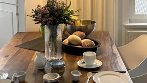 A dining table with a vase of flowers, bread, and tea set. - Farmhouse - Farmhouse apartment 25 (Sankt Peter-Ording)