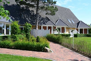 A building with a sloped roof, a brick pathway, and well-maintained greenery.