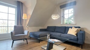 Uma sala de estar moderna com um sofá cinzento, uma mesa de centro de vidro e um abajur.