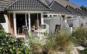 A house with a covered patio, a dining table, and chairs. - Luna19 (Room category) - Luna II (Sankt Peter-Ording)