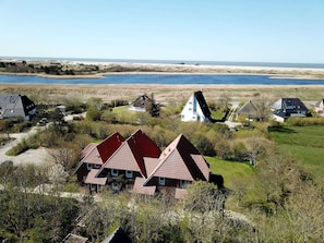 Uma vila costeira com casas tradicionais, uma praia de areia e mar calmo.