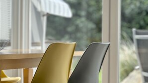 Une vue à travers une fenêtre, avec une chaise et une table.