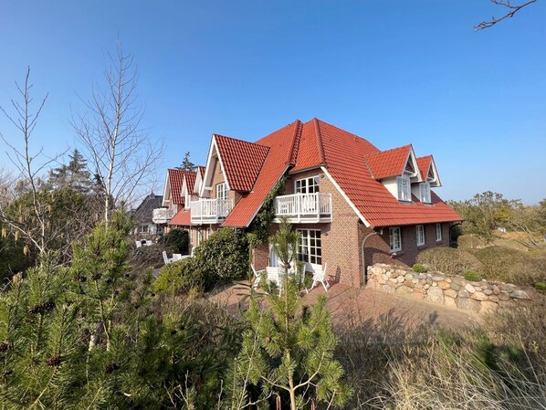 Une grande maison avec un toit rouge, de nombreux balcons et des fondations en pierre.