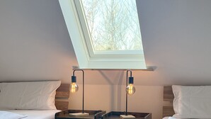 A bedroom with two beds, a skylight, and two wall-mounted lamps. - Luna18 (Room category) - Luna II (Sankt Peter-Ording)