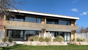 Una casa moderna de dos pisos con techo plano, ventanas amplias y fachada de piedra.
