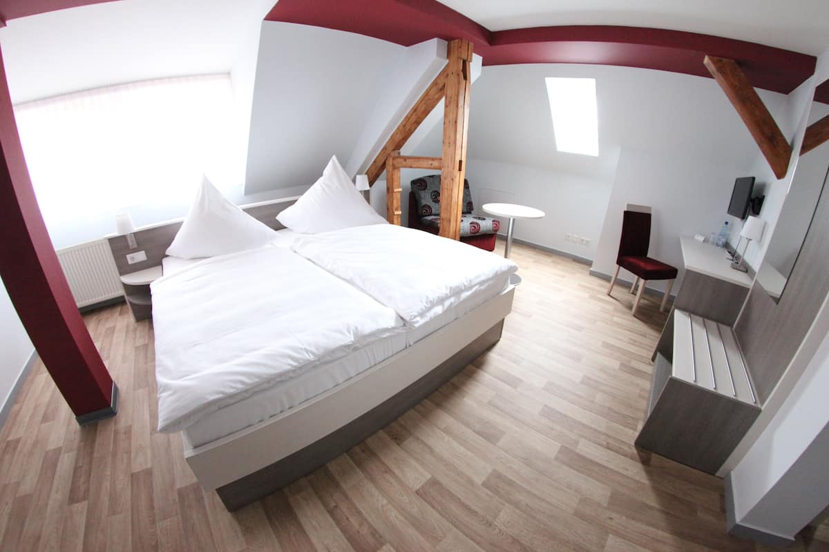A modern bedroom with a large bed, a small desk, and a chair.