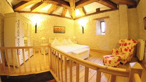 Quarto com teto de madeira, uma cama, uma cadeira e uma mesa de cabeceira.
