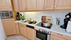 A compact kitchen with wooden cabinets, a microwave, a coffee maker, a sink, and a stove.