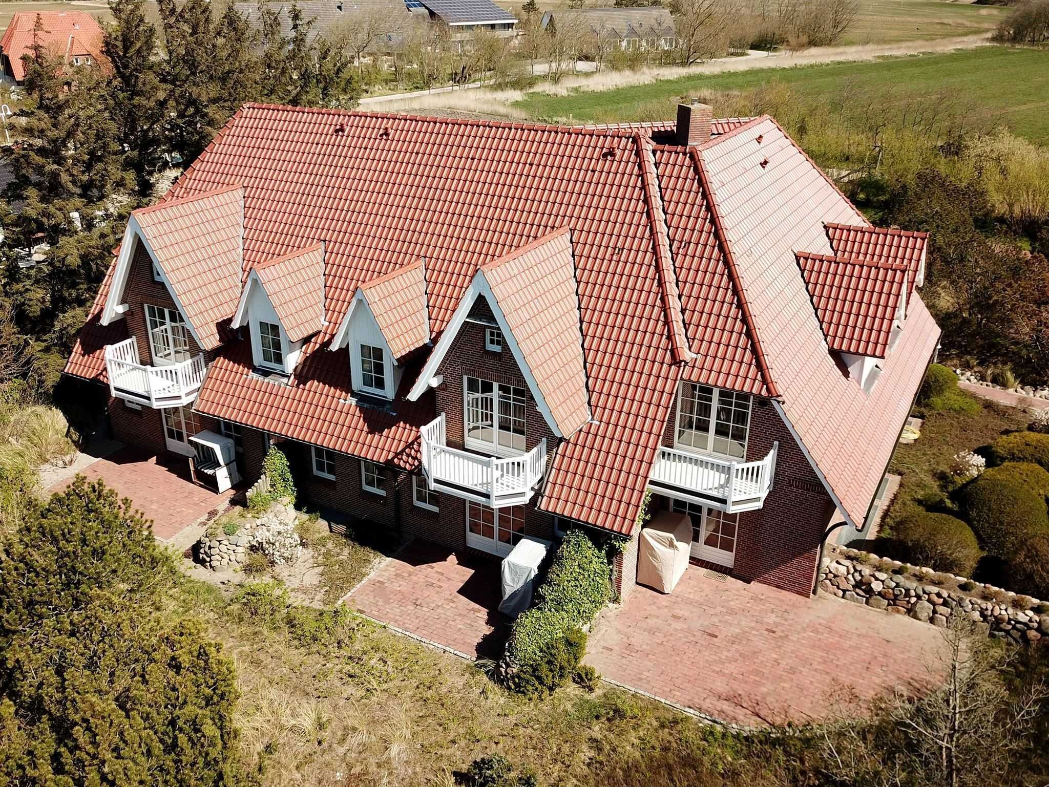A large, two-story house with a red-tiled roof and multiple balconies.