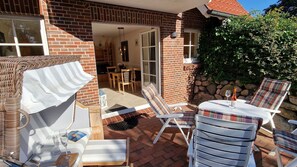 Une terrasse avec des meubles d’extérieur, un mur en briques et un mur en pierres.
